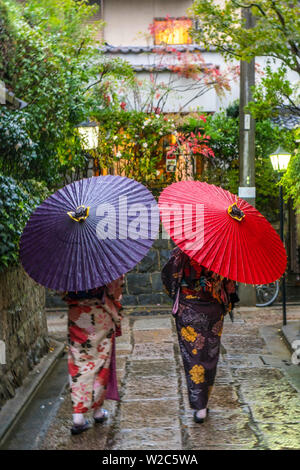 Women in traditional dress with umbrellas walking through Kyoto, Japan Stock Photo