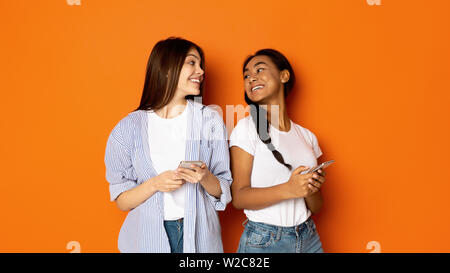 Teen girls looking at each other and using cellphones Stock Photo