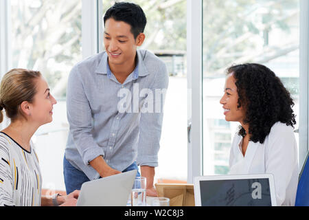 Team of positive business people discussing ideas and strategy of developments at meeting Stock Photo