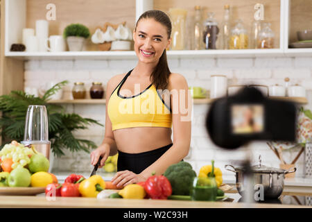 Healthy vlog. Slim woman cooking salad for new vlog, recording video Stock Photo