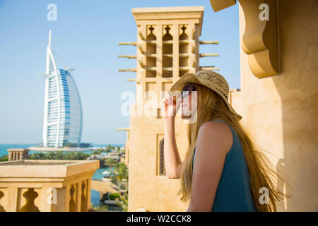 Woman loooking out over Madinat Jumierah and Burj Al Arab hotel, Dubai, United Arab Emirates (MR) Stock Photo