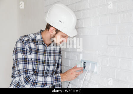 The master repairs the socket with a screwdriver installing it into the wall. Stock Photo