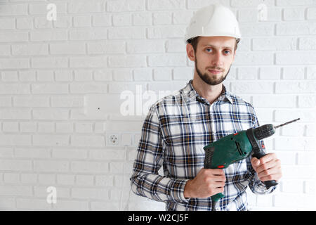 Man repairer in protective hard hat with hsmmer drill Stock Photo
