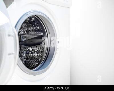 Close-up of clean white washing machine door with empty drum on white background with copy space. Stock Photo