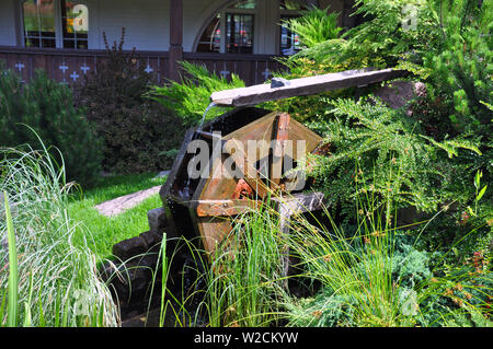 Landscape and arrangement. Driving mill wheel with falling water in the garden. Stock Photo