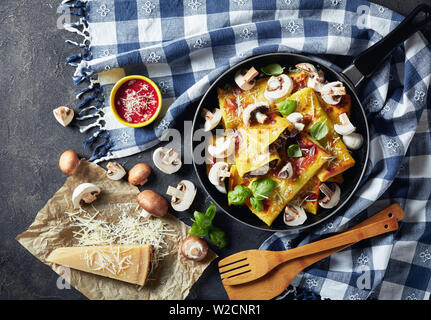 overhead view of Crepes with parmesan and mushrooms filling on a skillet on a concrete table with ingredients and kitchen towel, horizontal view from Stock Photo
