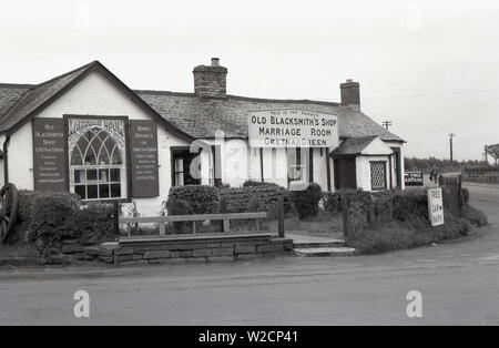 1950s, historical, Exterior of the Old Blacksmith's Shop, at Gretna Green, Scotland. A wedding venue since 1754, it is  famous for its 'Marriage Room', which held so -called 'runaway marriages', as Scottish law was different to that in England, where one had to be 21 and get married in a church. In Scotand, one could marry on the spot, in a simple 'marriage by declaration, only requiring two witnesses and assurances from the couple that they were both free to marry and as Gretna was just over the border from England, many did. Built in 1713, it sits at the junction of five old coaching roads. Stock Photo