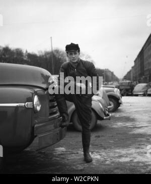 Motorcyclist in the 1950s. A young man dressed in the typical way the motorcyclists did in the 1950s. All leather. Leather boots, trousers and jacket. A kidney belt and a typical motorcyclist cap. Sweden December 1954 Stock Photo