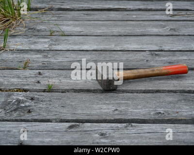 sledgehammer on the boards old bridge sticking rusty nails Stock Photo