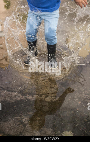 3 years boy having fun at urban puddle. Ground view Stock Photo