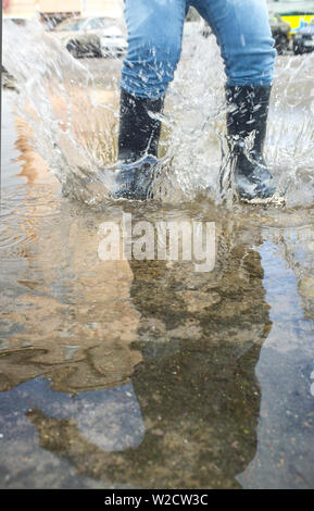 3 years boy having fun at urban puddle. Ground view Stock Photo