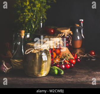 Jars with variety of traditional preserved fermented farm organic seasonal vegetables and fruits  on dark rustic background. Autumn canning. Conservat Stock Photo