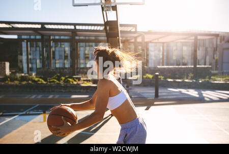 Young woman playing streetball on summer day. Female streetball player in action. Stock Photo