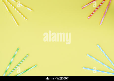 Multi-colored cocktail straw plastic tubes on a bright yellow background. Top view, copy space. Place for text. Stock Photo