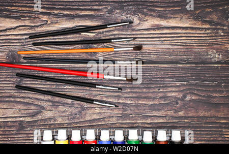 Brushes different size and watercolors on wooden background Stock Photo