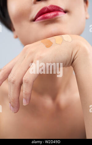 Close-up of young woman with different colors of foundation cream on her hand choosing one for her face Stock Photo