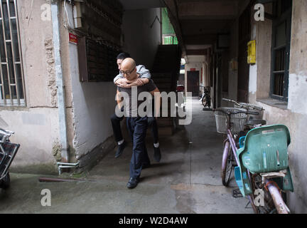 (190708) -- LINHAI, July 8, 2019 (Xinhua) -- Zhang Hailin carries Wu Yuanmiao to take part in a public service activity in Linhai City, east China's Zhejiang Province, June 27, 2019. Wu Yuanmiao, when working as a barber, set a rule for himself to provide free service one day a week to the old, the disabled, and soldiers. Having served more than 60,000 customers for 17 year, he is the winner of various awards including May 1 Labor Medal. However, diagnosed with brain disease, Wu's condition has been worse off since 2008. In 2014, he experienced a hard time in running his barber shop and pro Stock Photo