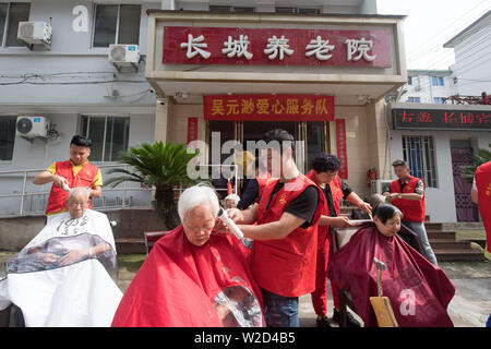 (190708) -- LINHAI, July 8, 2019 (Xinhua) -- Volunteers cut hair for free at a nursing home for the aged in Linhai City, east China's Zhejiang Province, June 27, 2019. Wu Yuanmiao, when working as a barber, set a rule for himself to provide free service one day a week to the old, the disabled, and soldiers. Having served more than 60,000 customers for 17 year, he is the winner of various awards including May 1 Labor Medal. However, diagnosed with brain disease, Wu's condition has been worse off since 2008. In 2014, he experienced a hard time in running his barber shop and providing public s Stock Photo