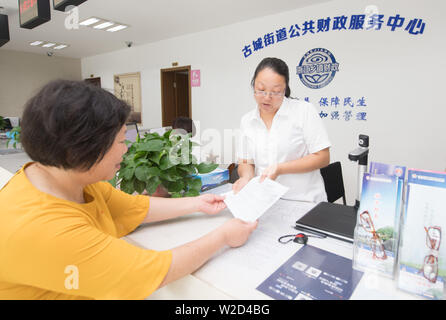 (190708) -- LINHAI, July 8, 2019 (Xinhua) -- Fang Huafen (L), an official of Lucheng community, applies for relief fund for Wu Yuanmiao at a service center in Linhai City, east China's Zhejiang Province, June 27, 2019. Wu Yuanmiao, when working as a barber, set a rule for himself to provide free service one day a week to the old, the disabled, and soldiers. Having served more than 60,000 customers for 17 year, he is the winner of various awards including May 1 Labor Medal. However, diagnosed with brain disease, Wu's condition has been worse off since 2008. In 2014, he experienced a hard tim Stock Photo