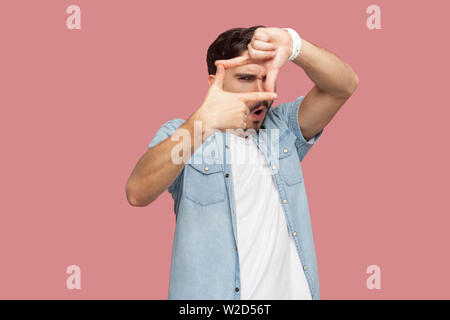 Portrait of attentive handsome bearded young man in blue casual style shirt standing crop composition focus hand gesture and looking at camera . indoo Stock Photo