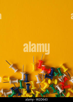 Colorful pushpins on a yellow background with space for text Stock Photo