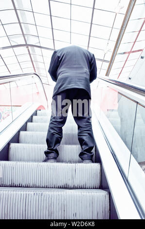 man in suit going up with an escalator Stock Photo