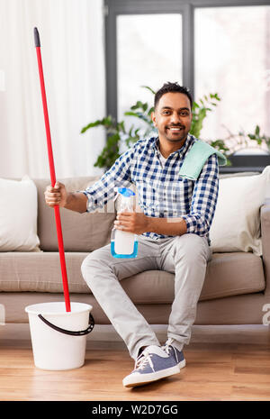 indian man with mop and detergent cleaning at home