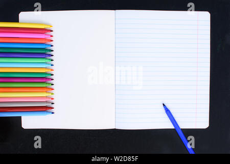 Open multicolored markers closeup on an open notebook in the line. Place for text. Stock Photo