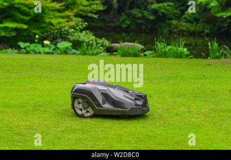 Nagoya, Japan - Jun 29, 2019. Automatic lawn mower robot moves on the grass at botanic garden. Stock Photo