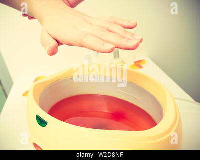 Handcare, beauty studio wellness treatments concept. Woman getting paraffin hand treatment at spa salon. Stock Photo