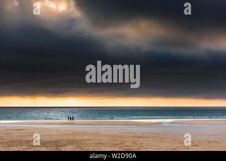 A group of people hanging out on the beach in a beautiful golden sunset at Fistral in Newquay in Cornwall. Stock Photo