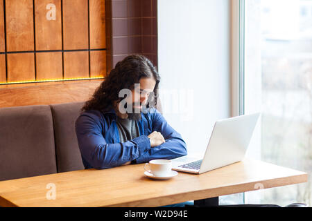 Portrait of tired handsome young adult man freelancer in casual style sitting in cafe with laptop, sleeping after hard overtime work, closed eyes buss Stock Photo