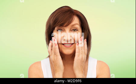 portrait of smiling senior woman touching her face Stock Photo