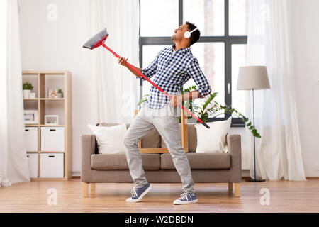 man with broom cleaning and having fun at home Stock Photo