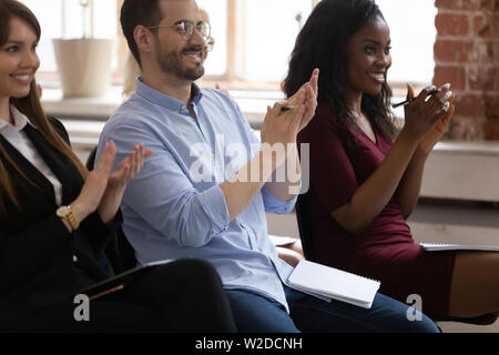 Diverse happy business team audience group applauding sit on chairs Stock Photo