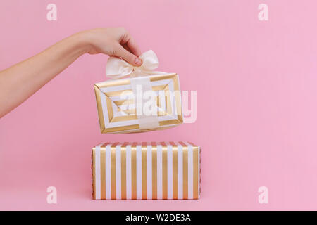 Womans hands holding gift or present box on pink pastel background. Stock Photo