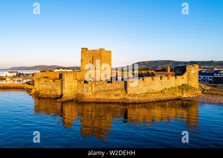 Medieval Norman Castle in Carrickfergus near Belfast in sunrise light. Aerial view with water reflection