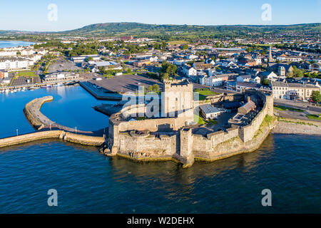 Medieval Norman Castle in Carrickfergus near Belfast in sunrise light. Aerial view with marina, yachts, parking and town