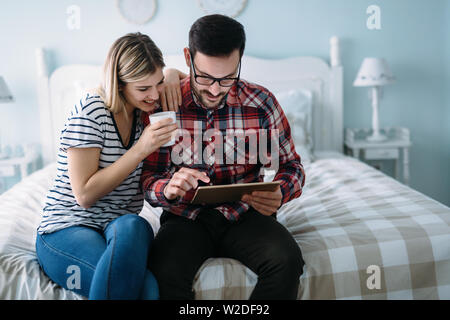 Young happy couple using tablet in bedroom Stock Photo