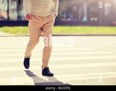 senior man walking along city crosswalk Stock Photo