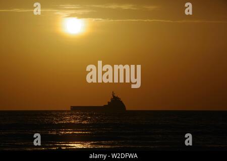 Silhouetted Oil Support Vessel on the North Sea Offshore Aberdeen at Sunrise. Scotland, UK. Stock Photo