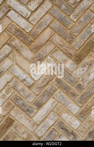 Close up of the mottled surface pattern and texture of handmade yellow stock bricks laid in a Herringbone pattern. Stock Photo