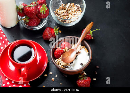 Homemade baked granola with Yogurt  and strawberries in ceramic bowl and cup of black coffe for breackfast, healthy food concept Stock Photo