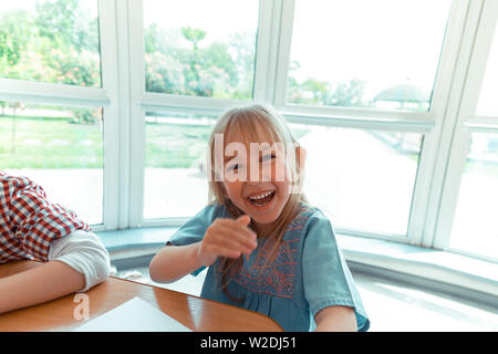 Happy blonde girl sitting at the table Stock Photo