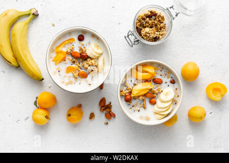Granola breakfast with fruits, nuts, milk and peanut butter in bowl on a white background. Healthy breakfast cereal top view Stock Photo