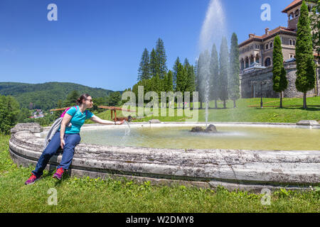 Young woman refreshing in the fountain in front of Cantacuzino castle in Busteni, Romania Stock Photo