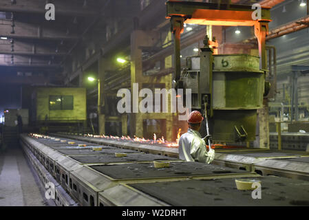 Workers in protective equipment in a foundry during the production of steel components - workplace industrial factory Stock Photo