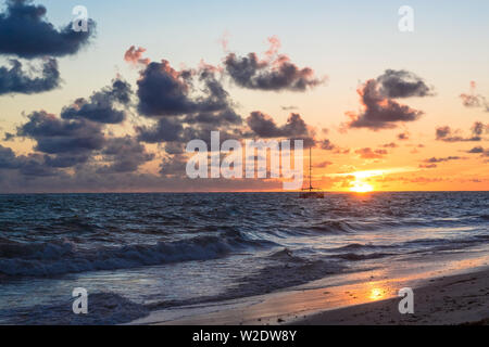 Fluffy dark clouds floating over turbulent ocean waters on sandy beach shore. Stock Photo