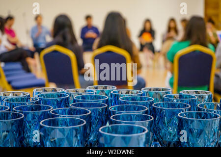 Close up to arranged blue luxury glasses behind the seminar workshop event. Glasses are prepared for the audiences and speakers in the circle group wo Stock Photo
