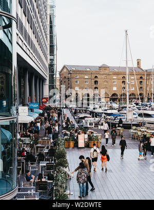 London, UK - June 22, 2019: People walking past restaurants and cafes in St. Katharine Docks, a former dock converted into marina and mixed-used comme Stock Photo